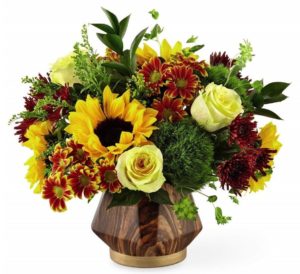 sunflowers with white roses and assorted yellow and green accents in brown vase