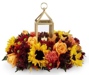 lantern surrounded by yellow and red fall flowers