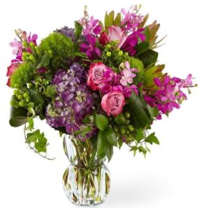 luxurious display of hydrangea, roses, orchids and lush greenery presented in a gorgeous heavyweight molded glass vase