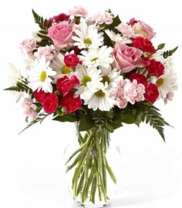 Pink mini carnations along with traditional white daisies and greenery are presented in a classic clear vase. 