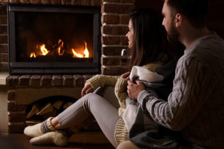 Lovely couple sitting on floor near fireplace at home. Winter vacation